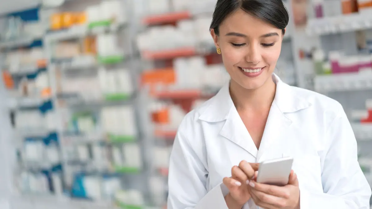 PTA steht in der Apotheke und tippt auf dem Handy
