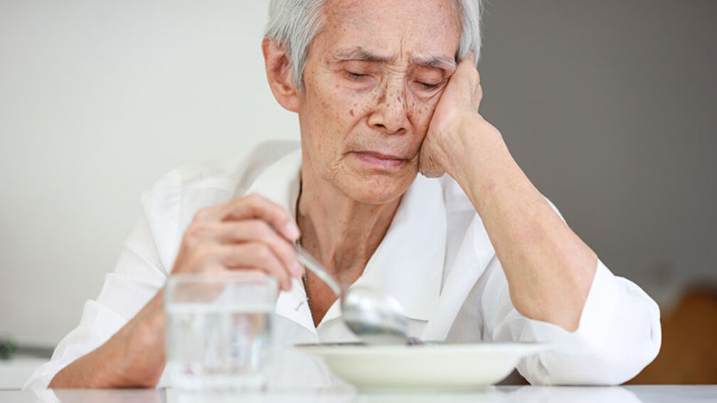 Seniorin stochert lustlos in ihrem Essen